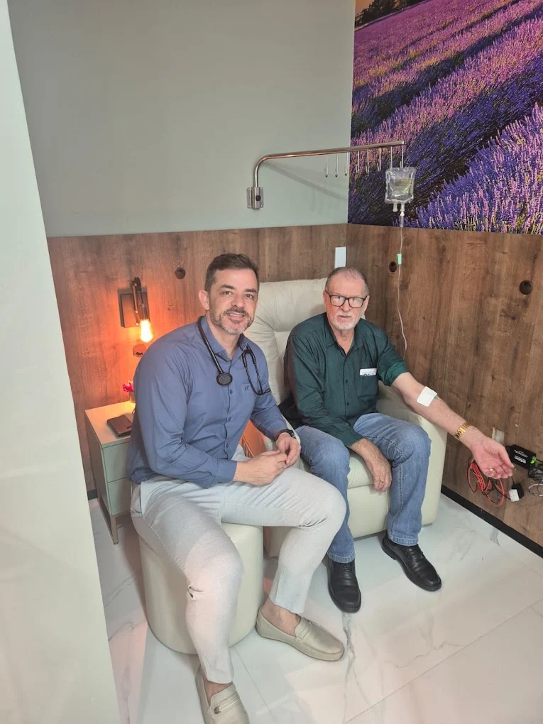 Dr. Júnior Pasin acompanhando um paciente na sala de infusão da clínica